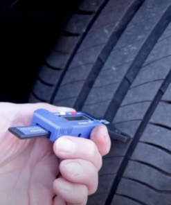 A person's hand pushes the digital tyre tread depth gauge from PCL into the tyre of a car