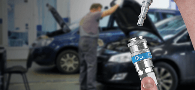 Image of a PCL coupling in a car garage which shows a man opening a car bonnet in the background
