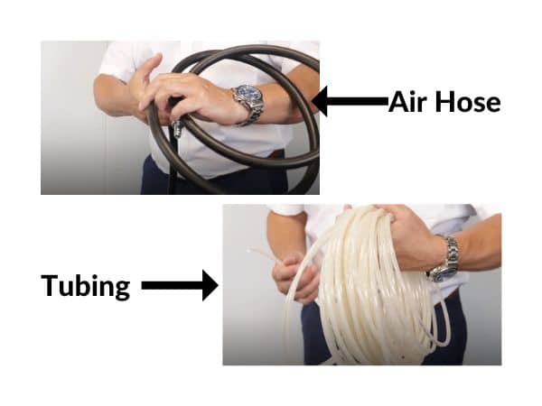 A man holds a reel or air line hose and a reel of air tubing to show the differences