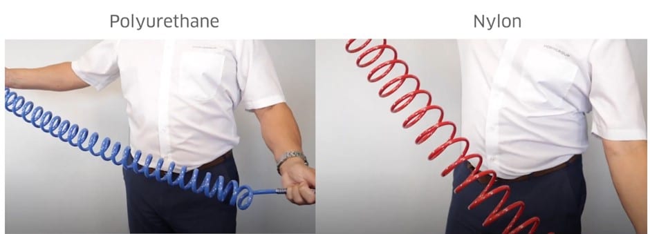 A person showing the difference between a polyurethane coiled hose and a nylon coiled hose by pulling on them.