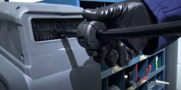 A gloved hand in a workshop pulls the retractable air hose reel to use it.