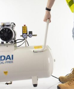 A man in a hi-viz top pulls the compressor by its handle
