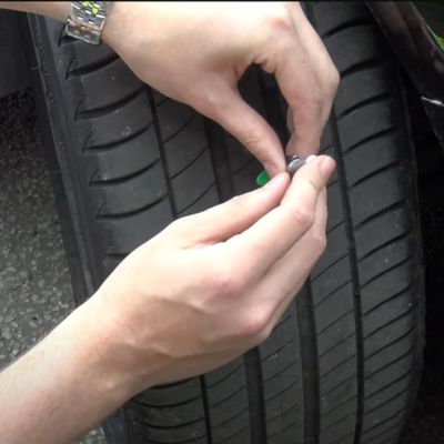 The base of the tread depth gauge is pushed down to measure the depth of the tyre