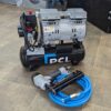 Photo taken from Metro Sales Air Compressor shop showing the PCL 8L air compressor on the floor grouped with a blue PVC air hose with safety coupling and a PCL Staple / Nail gun.