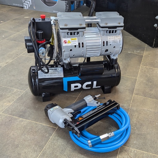 Photo taken from Metro Sales Air Compressor shop showing the PCL 8L air compressor on the floor grouped with a blue PVC air hose with safety coupling and a PCL Staple / Nail gun.