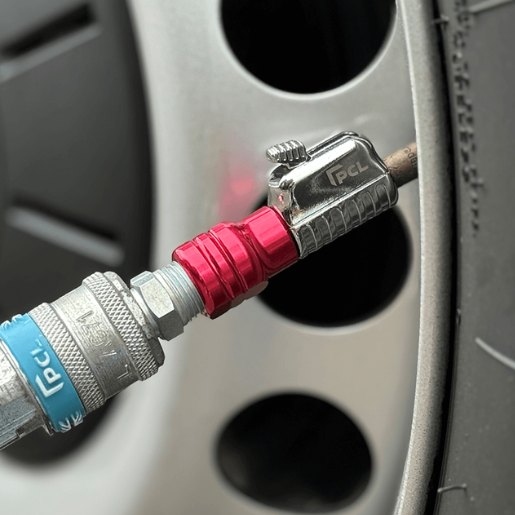 The silver and red closed tailpiece tyre connector from PCL attached to the wheel of a car.