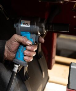 A man's hand holds the PCL Prestige stubby impact wrench in his hand as he works on a car. The image is a close up of his oil covered hand holding the impact wrench.