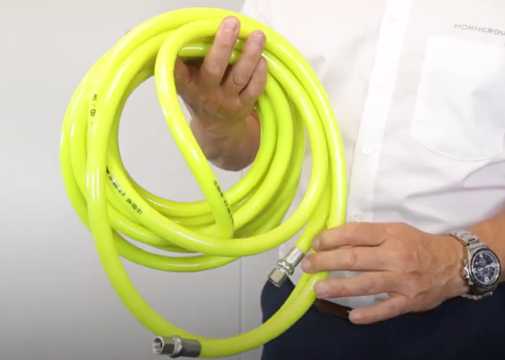 A high vis air line hose with couplings held by a man in a white shirt